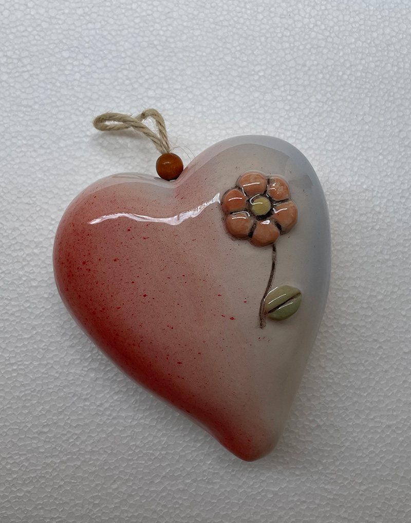 Pendente in ceramica. A forma di piccolo cuore con fiore in rilievo. Misure cm 11x11x6. Fatto a mano. Pezzo unico.