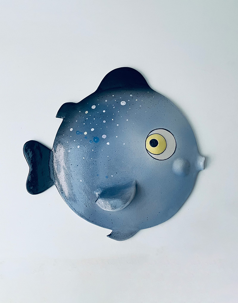 Three-dimensional sculpture of a blue puffer fish for hanging, made of refractory clay and decorated with engobes, oxides, glazes and polished crystaline. Measures 54 cm x 54 cm