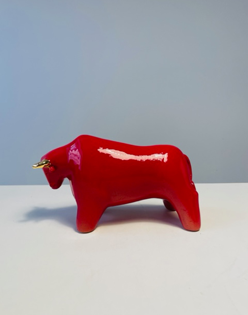 Toro in ceramica smaltata rosso lucido con decori in oro zecchino a terzo fuoco. Lunghezza 20 cm. Altezza 12 cm.
